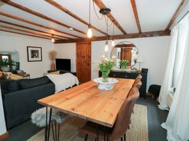 A dining area with a wooden table and chairs next to a living room with a sofa and television at Penyrgrisiau in Barmouth
