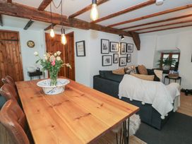 A dining table with chairs and flowers next to a living area with a sofa and framed pictures on the wall at Penygrisiau in Barmouth
