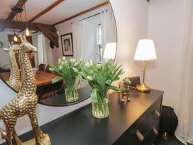A black dresser with a lamp giraffe and vase of flowers in front of a round mirror at Penyrgrisiau in Barmouth