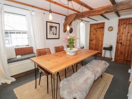 A dining room with wooden table chairs fur-covered bench and exposed wooden beams at Penygriasiau in Barmouth