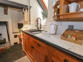 A kitchen sink with mugs kettle and coffee bar items on a counter with wooden cabinets at Penyrgrisiau in Barmouth