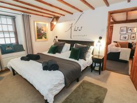 A bedroom with a bed with green and gray pillows black rolled towels and a nightstand with a lamp at Penyrisiau in Barmouth
