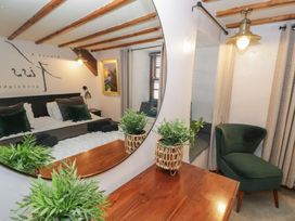 A bedroom with a bed reflected in a round mirror a green chair and a wooden table with plants at Penygrisiau in Barmouth