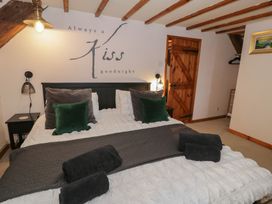 A bedroom with a large bed green and gray cushions wooden door and ceiling beams at Penyrgrisiau in Barmouth