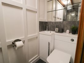 A bathroom with a white toilet a small sink a mirror and a toilet paper holder at Penygrisiau in Barmouth