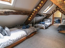 A bedroom with three single beds under a sloped ceiling and wooden beams at Penygrisiau in Barmouth