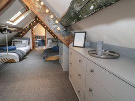 A bedroom with two single beds under a sloped ceiling with exposed wooden beams a dresser and an open door leading to a bathroom at Penyrgrisau in Barmouth