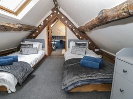 A bedroom with two single beds with grey headboards under sloped ceilings and exposed wooden beams at Penyrgysiau in Barmouth