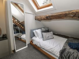 A small bedroom with a single bed under a skylight window a large wooden beam above the bed a floor mirror leaning against the wall and carpeted floor at Penygrisiau in Barmouth