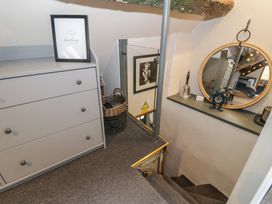 A small landing area with a grey chest of drawers a basket framed pictures and a round mirror at Penygrisiau in Barmouth