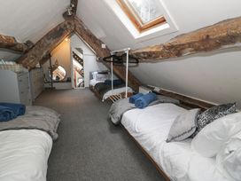 An attic bedroom with exposed wooden beams three beds a skylight window a mirror and a dresser at Penyrgrisiau in Barmouth