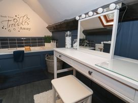 A bathroom with a bathtub a vanity table with mirror and stools at Penyglaisau in Barmouth