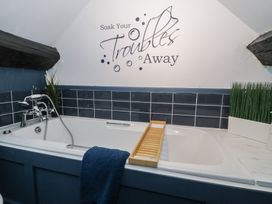 A bathroom with a bathtub next to wall tiles and plants at Penygriasiau in Barmouth