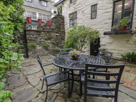 An outdoor patio area with a round metal table and four chairs on stone flooring at Penygrisiau in Barmouth