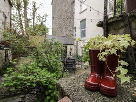 A garden area with red boot planters and green plants outside stone buildings at Penygrisiau in Barmouth