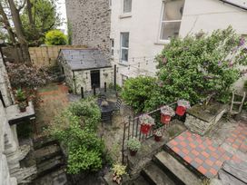 An outdoor patio with stone steps tables chairs plants and potted flowers at Penygriasiau in Barmouth