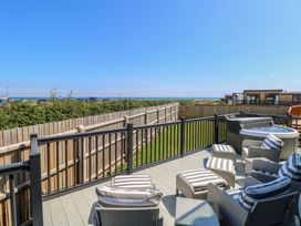 An outdoor seating area with a hot tub overlooking the sea at Life's a Beach Bacton