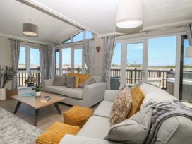 A living room with seating and large windows at Life's a Beach in Bacton
