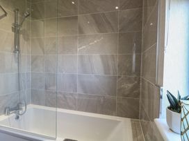 A bathtub with a showerhead and glass screen at Life's a Beach in Bacton