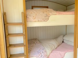 A wooden bunk bed with pink floral bedding and pillows at Shepherd Hut 1 in Northchapel