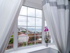 A living room window with curtains and an orchid at 45 North View in Brixham