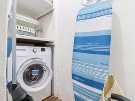A laundry room with a washing machine and ironing board at 45 North View in Brixham
