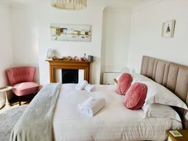 A bedroom with a bed, armchair, and fireplace at Lizzy’s Cottage Brixham