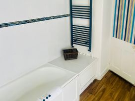 A bathroom with a bathtub and towel rack at Lizzy’s Cottage Brixham