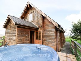 An outdoor view of a wooden cabin beside a hot tub at Pen Y Clawdd near Beggar's Bush