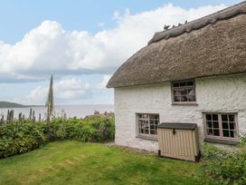 A cottage with a thatched roof and garden area at Mermaid Cottage in Coverack near St Keverne