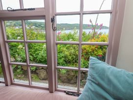 A window with flowers and a cushion in the sitting room at Mermaid Cottage near Coverack