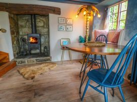 A snug with a wood stove and a round table at Mermaid Cottage in Coverack near St Keverne