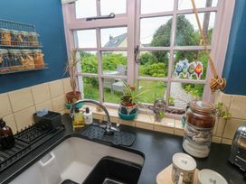 A kitchen with sink and window overlooking garden at Mermaid Cottage in Coverack near St Keverne