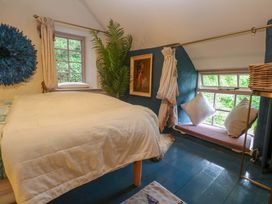 A bedroom with a bed, window and plant at Mermaid Cottage in Coverack near St Keverne