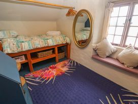 A bedroom with a bed and mirror at Mermaid Cottage in Coverack near St Keverne