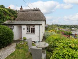 A house with a thatch roof and garden furniture at Mermaid Cottage in Coverack near St Keverne