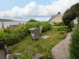 A garden with a table and chairs overlooking water at Mermaid Cottage in Coverack near St Keverne