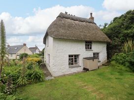 A cottage with a thatched roof surrounded by a garden at Mermaid Cottage in Coverack near St Keverne