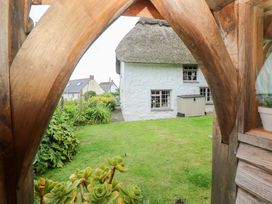 A garden view with a thatched roof house and a shed at Mermaid Cottage in Coverack near St Keverne