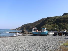 A boat and tractor on a beach near water at Mermaid Cottage in Coverack near St Keverne