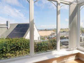 A conservatory with a view of a beach and houses at 22 Pentire Avenue in Newquay