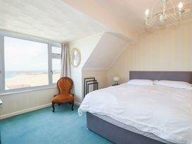 A bedroom with a bed and a chair at 22 Pentire Avenue Newquay