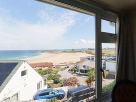 A view of the beach and ocean through a window at 22 Pentire Avenue in Newquay