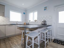 A kitchen with cabinets and bar stools at Pipers in Newquay
