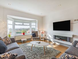 A living room with sofas armchair coffee table wall mounted TV and electric fireplace at Bryn Derw in Caernarfon