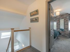 Upstairs hallway with framed pictures on wall and view into bedroom with textured wall at Bryn Derw in Caernarfon