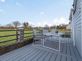 An outdoor deck with a table and four chairs overlooking a grassy field with sheep at Bryn Derw in Caernarfon