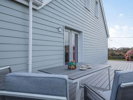 An outdoor deck with two chairs and a table with cups and a flower box at Bryn Derw in Caernarfon