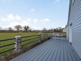 A patio with chairs and a table overlooking a grassy field with sheep at Bryn Derw in Caernarfon
