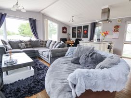 A living room with grey sofas a dining table kitchen island and wall art at 155 Woodland Hall Lyons in Ruthin